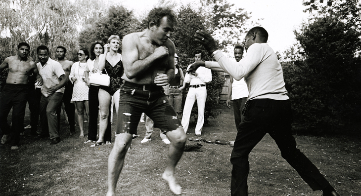 black and white image of two men boxing in a yard